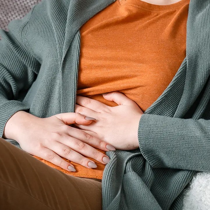 Mujer con molestias digestivas reflejando hinchazón y pesadez abdomina