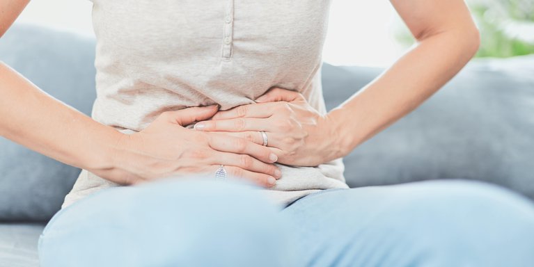Mujer con dolor abdominal causado por digestión lenta y hinchazón, un problema común que afecta el bienestar digestivo y la salud intestinal